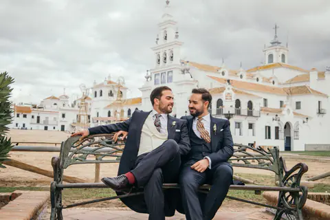 The couple sitting on a wrought-iron bench in front of the El Rocío hermitage in Almonte (Huelva)
