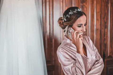The bride on the phone while getting ready, hair done and headpiece on