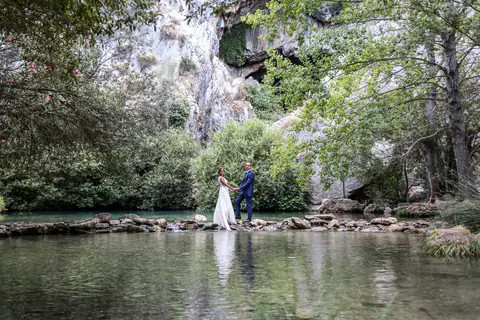 The couple by a river surrounded by greenery